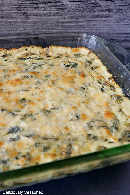 A glass 13 by 9 baking dish filled with spinach artichoke dip.