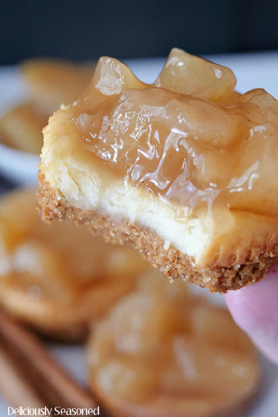 A super close up photo of a mini apple cheesecake with a bite taken out of it.
