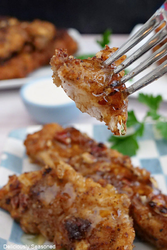 A close up photo of a bite of chicken on a fork with honey on it.