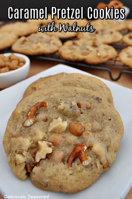 Two caramel pretzel cookies on a white plate with more cookies in the background on a wire rack.