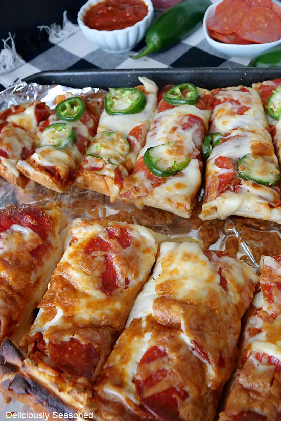 A baking sheet covered with aluminum foil with two halves of French bread pizza on it.