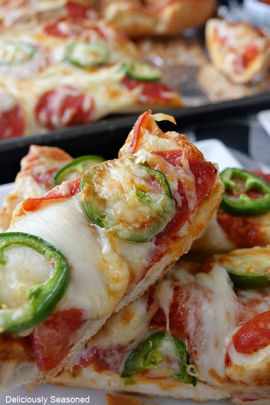 A super close up photo of two slices of French bread pizza showing the melted cheese, pepperonis and sliced jalapenos.