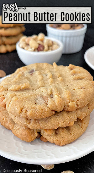 Peanut butter cookies stacked up on a white plate with small white bowls fill with peanut butter chocolate chips.