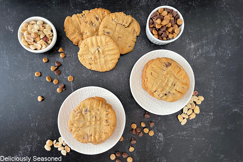 An overhead shot of peanut butter cookies on white plates with morsels scattered across the board.