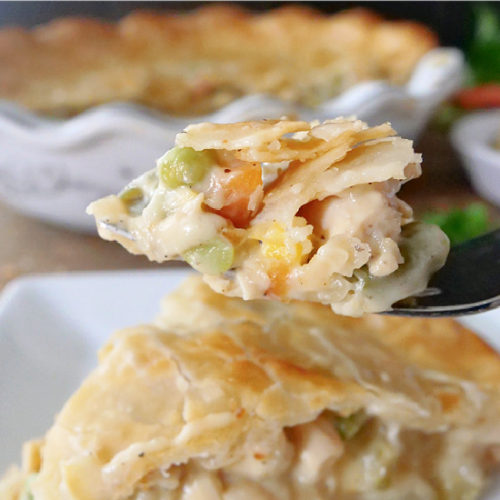 A bite of homemade turkey pot pie on a fork held up over more on the plate.