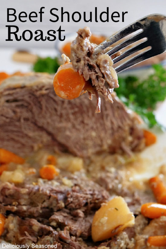 A close up photo of a fork with a bite of roast and carrot on it.