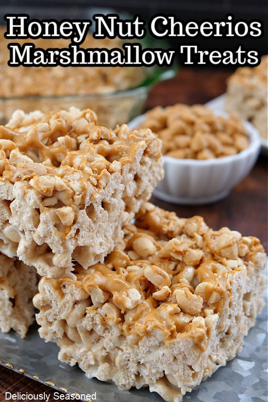 Honey Nut Cheerios Marshmallow Treats stacked on top of each other with a bowl of butterscotch chips in the background.