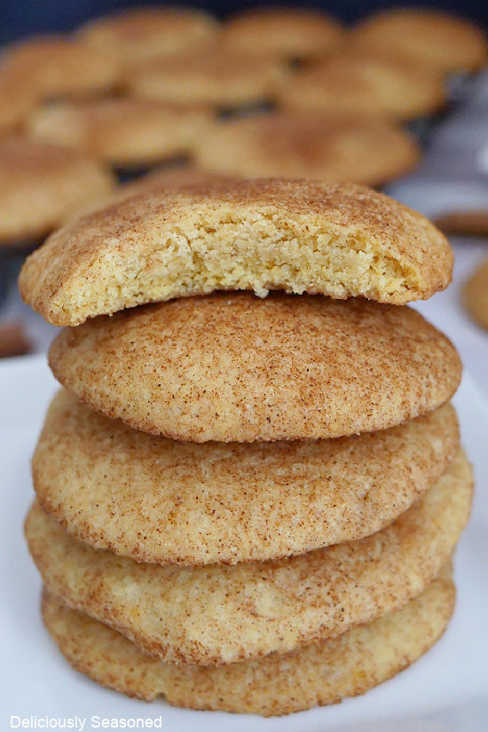 A close up photo of a stack of pumpkin snickerdoodle cookies with a bite taken out of one of the cookies.