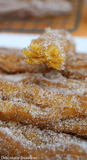 A close up photo of a churro with a bite taken out of it.