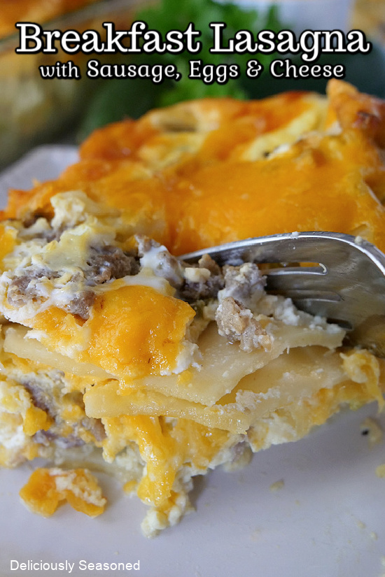 A slice of breakfast lasagna showing off the layers of noodles, cheese, eggs, and sausage. 