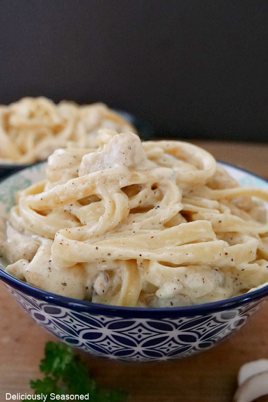 A white and blue bowl filled with creamy chicken fettuccine.