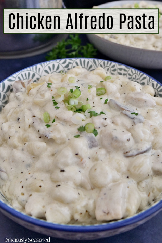 A large bowl of chicken alfredo in a bowl with blue trim.