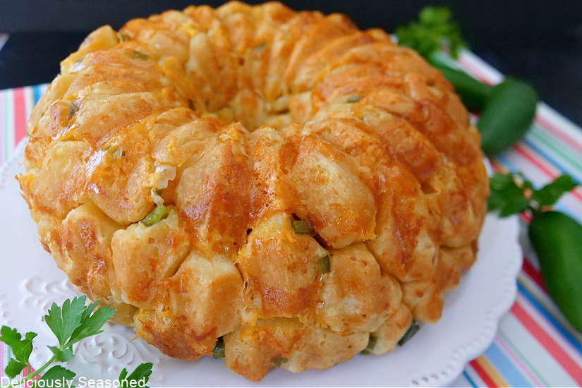 A Whole jalapeno cheddar monkey bread on a white plate with a striped colored placemat underneath.