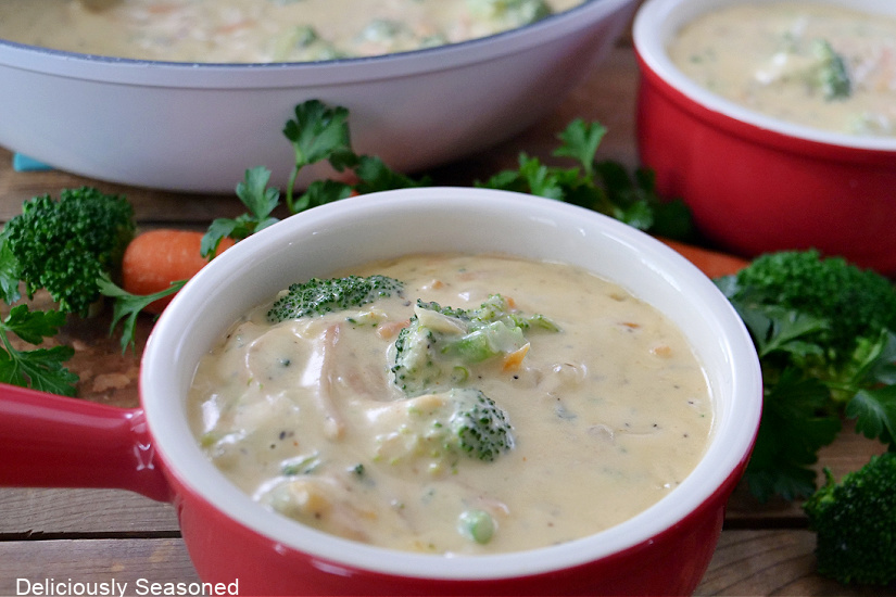 Two red soup bowls filled with broccoli cheddar soup.