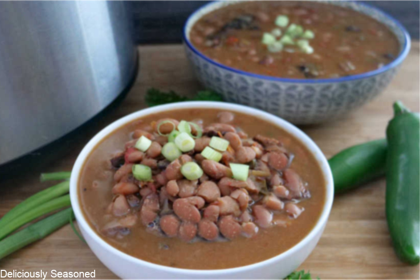Two bowls with beans in them with a crockpot off to the side.