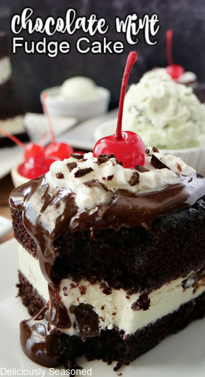 A slice of chocolate cake sitting on a white plate with hot fudge, whipped cream, and a cherry on top.
