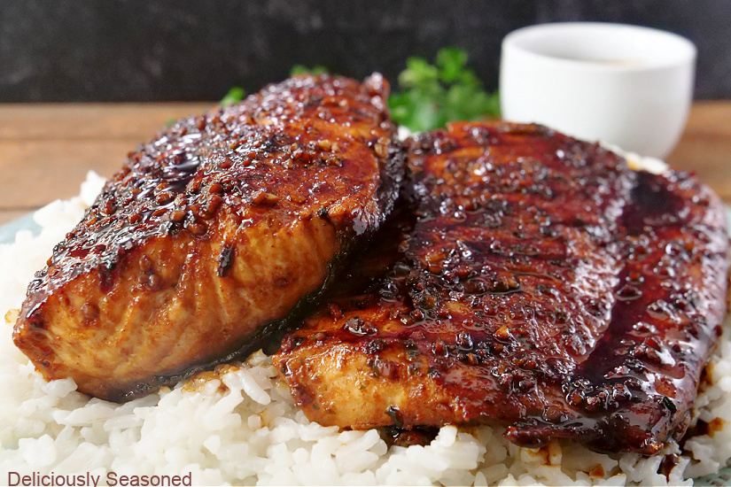 Perfectly coated salmon laying on a bed of white rice.