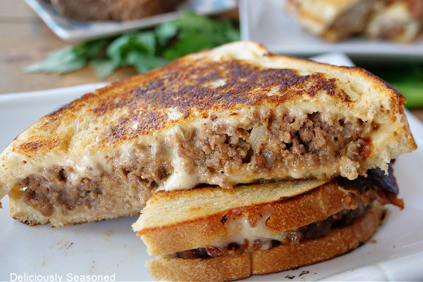 A grilled cheese sandwich with meatloaf on a white plate with pepper jack cheese on it. 