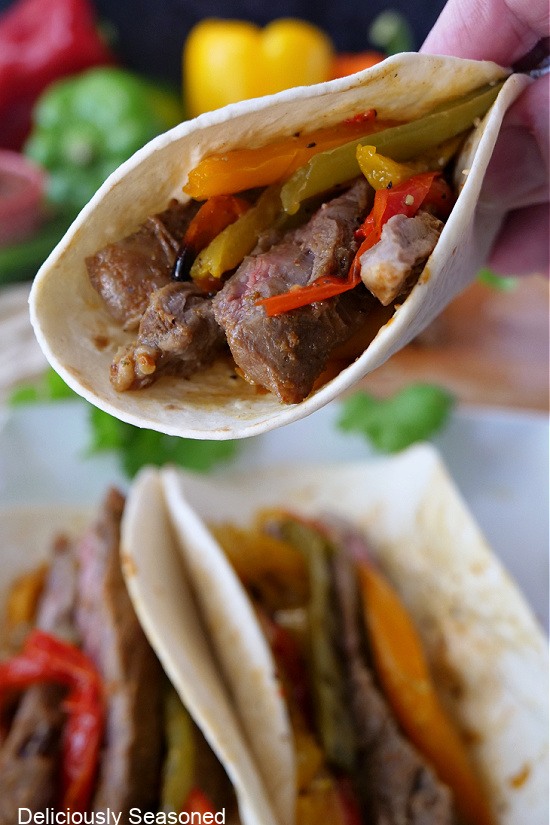 A flour tortilla filled with onions, bell peppers, and steak. 