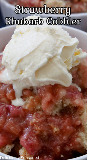 Strawberry Rhubarb Cobbler in a white bowl topped with ice cream.