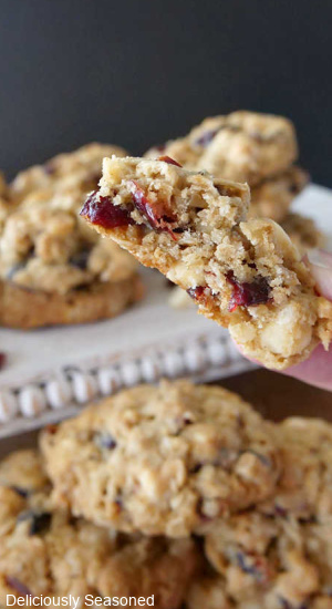Oatmeal cookies filled with craisins and white chocolate chips, with cookies in the background.