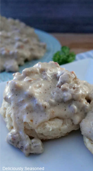 A close up of a biscuit with homemade sausage gravy on it.