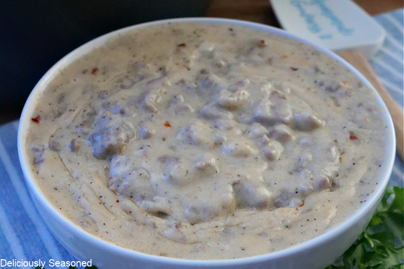 A close up of a white bowl filled with sausage gravy.