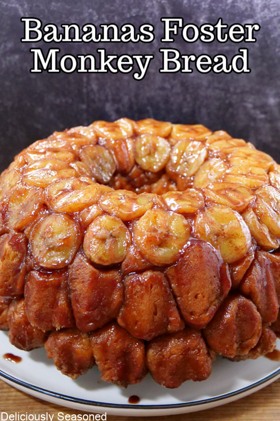 Bananas Foster monkey bread sitting on a white plate, covered in a sweet glaze.