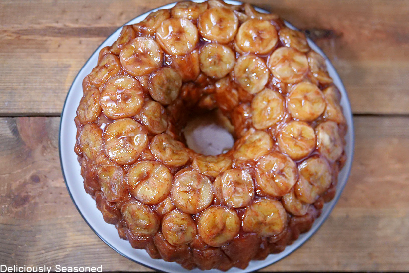 An overhead shot of the entire loaf of monkey bread, topped with sliced bananas and a delicious sauce.