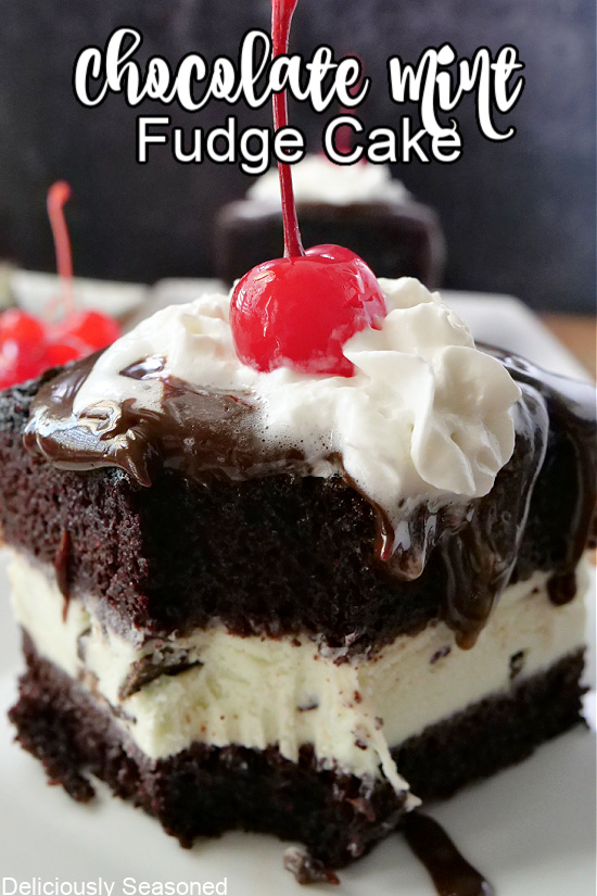 A slice of cake topped with hot fudge, whipped cream, and a cherry with a bite taken out of it.