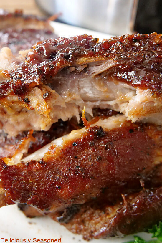 A close up photo of a few pork ribs piled on each other with the top one showing a bite taken out of it.