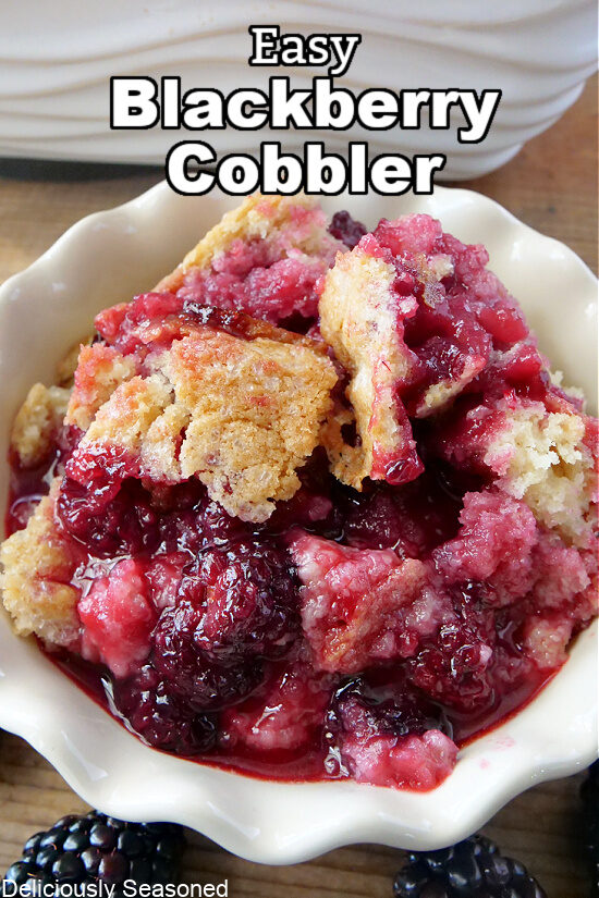 Blackberry cobbler in a white bowl with blackberries in the foreground and the title at the top.