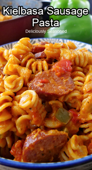 A close up of a blue bowl with a serving of pasta with rotini and kielbasa.