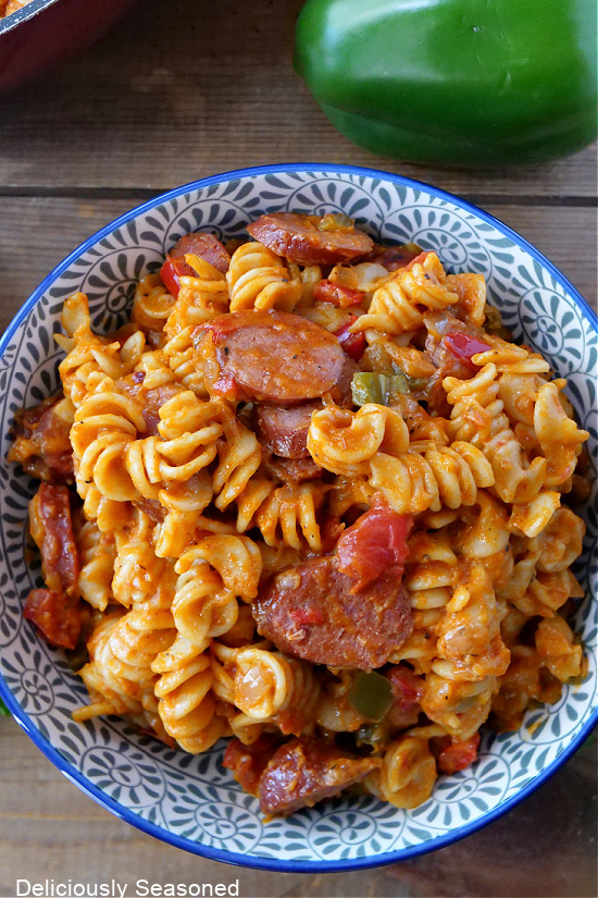 A white and blue bowl with blue trim loaded with kielbasa sausage pasta.