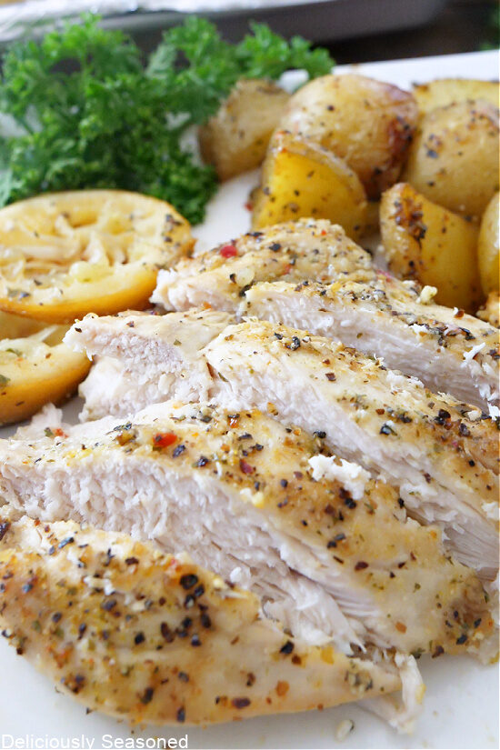 A close-up picture of a sliced lemon pepper chicken breast with potatoes in the background.