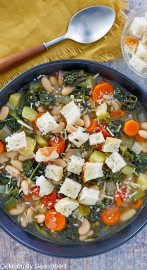 A bowl of Tuscan Vegetable Soup topped with chunks of bread.