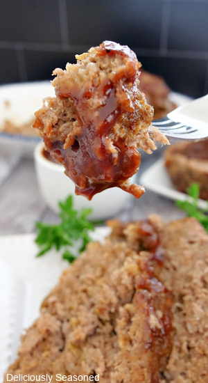 A bite of meatloaf on a fork covered in bbq sauce.