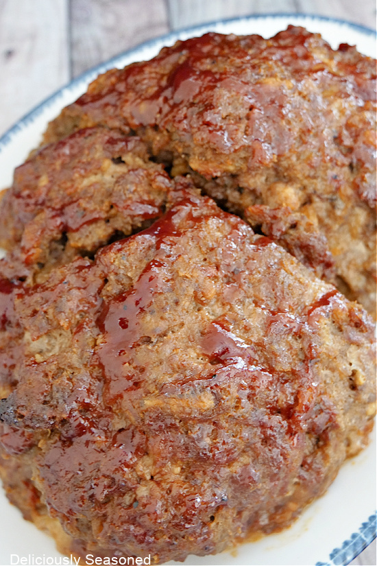 A full loaf of meatloaf sitting on a white plate, topped with BBQ sauce.