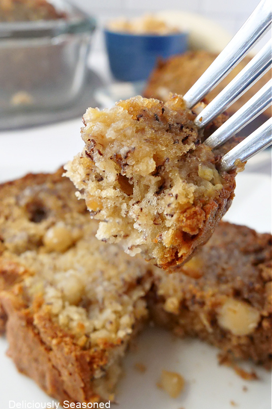 A big bite of banana bread being held up on a fork.