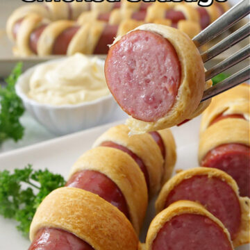 Slices of smoked sausage wrapped in crescent rolls and lined on a white plate.