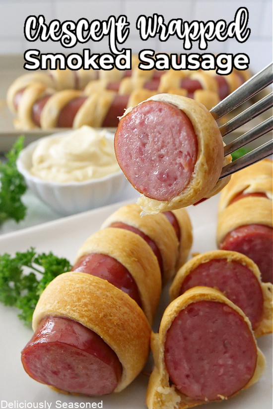 Slices of smoked sausage wrapped in crescent rolls and lined on a white plate.