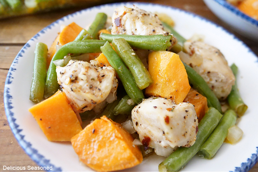 A white plate with diced, seasoned chicken, green beans, and diced sweet potatoes.