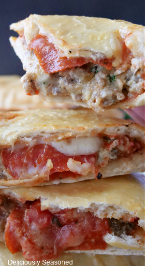 Calzones stacked up showing the pepperoni, Italian sausage, and mozzarella cheese.