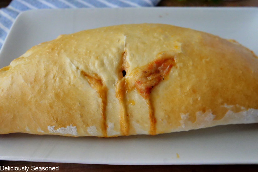 A full homemade calzone with three slits in the top of it.
