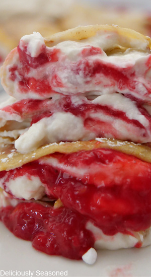 A super close up of crepes with homemade whipped cream and a raspberry filling.