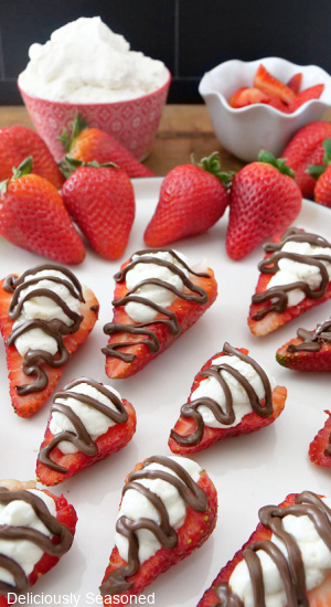 Stuffed strawberries laid out on a white with chocolate drizzled on top.