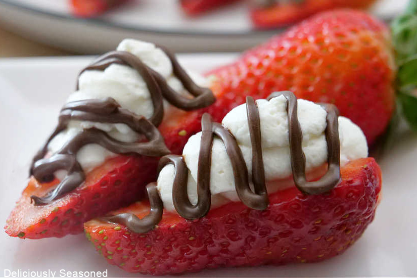Strawberries cut in half, topped with whipped cream, and drizzled with chocolate.