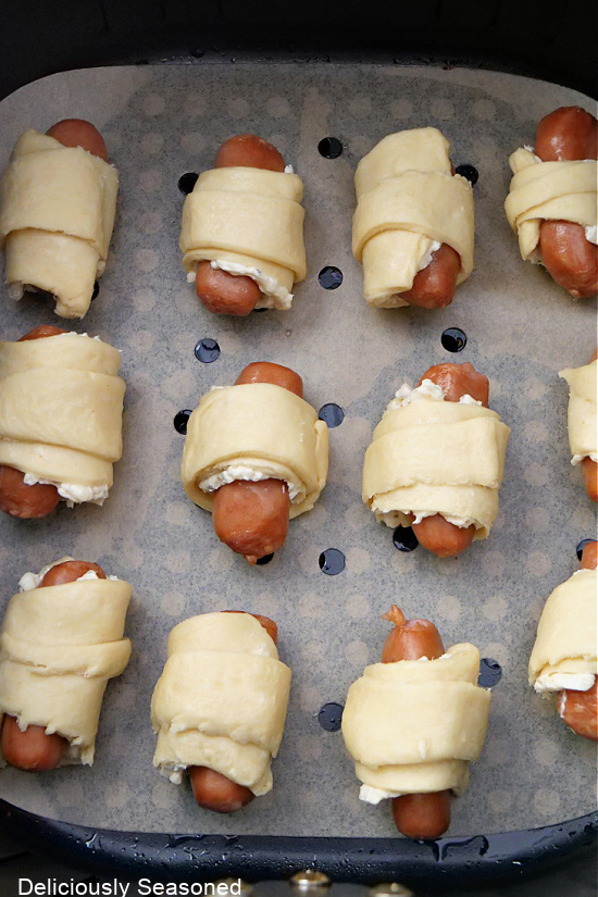 A close-up picture of the uncooked cheese pigs in a blanket in the air fryer basket.