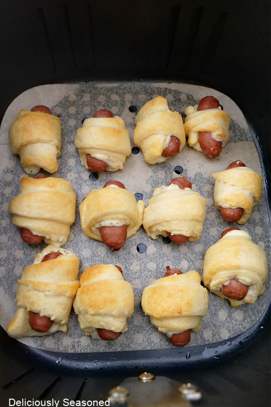 A picture of cheese pigs in a blanket in the air fryer basket.