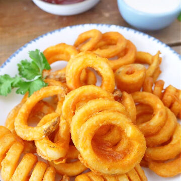 A white plate with blue trim loaded with crispy curly fries.